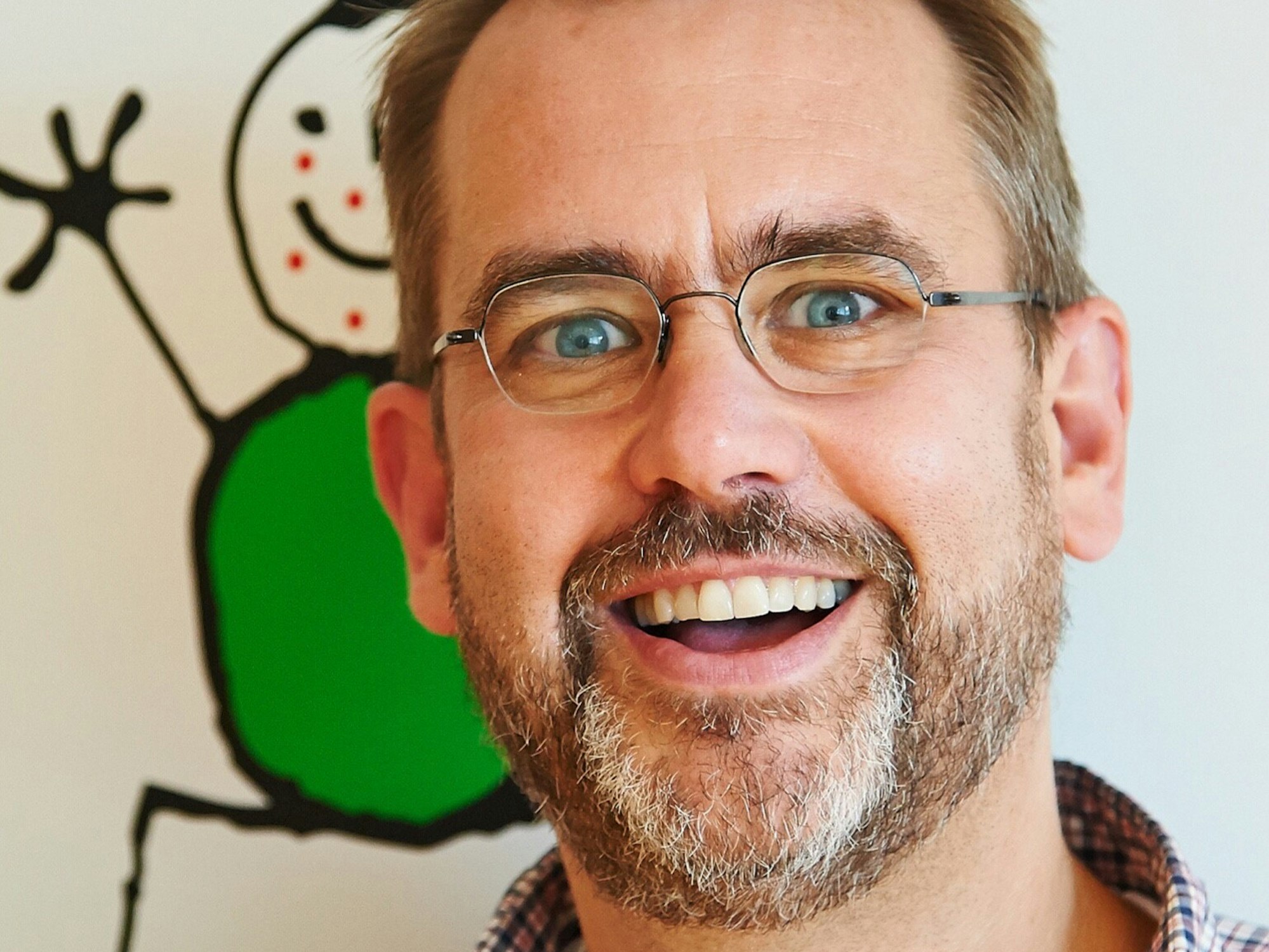 Anselm Bönte guckt in die Kamera. An der Wand hinter ihm ist eine Kinderzeichnung