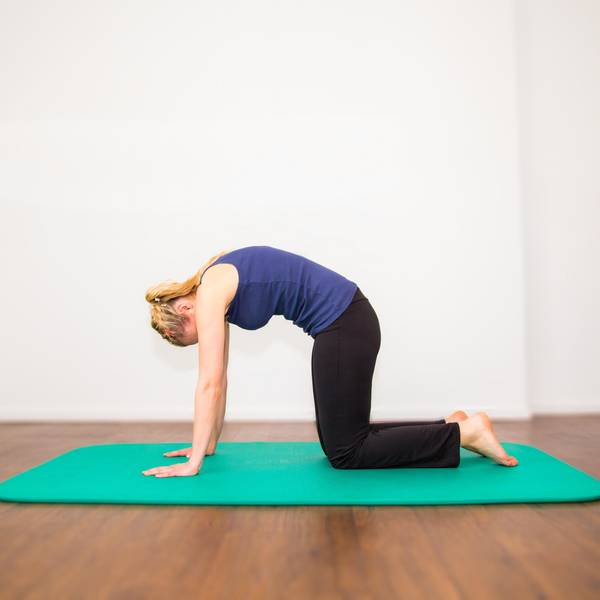 Frau_macht_im_Vierfüßlerstand_ein_Hohlkreuz_auf_Yogamatte