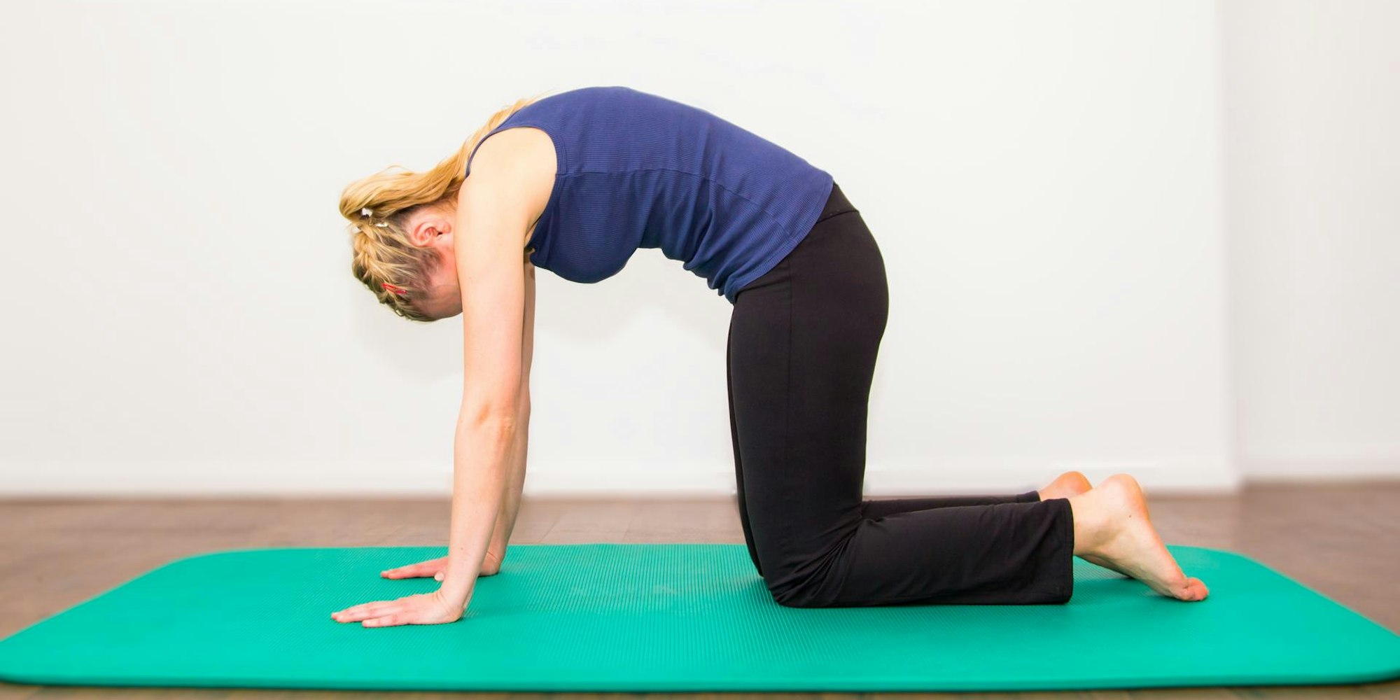 Frau_macht_im_Vierfüßlerstand_ein_Hohlkreuz_auf_Yogamatte