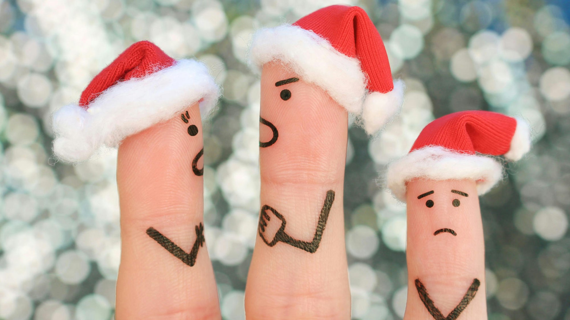 Drei Finger dekoriert als Weihnachtsmänner spielen einen Streit nach.