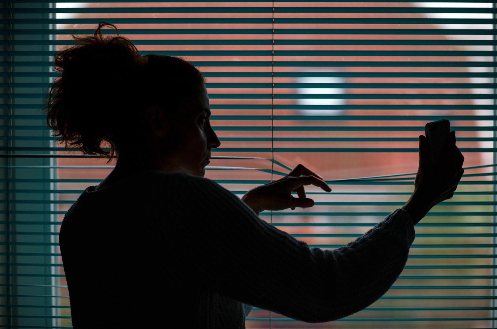 Stalking_Frau schaut aus Fenster_ Symbol