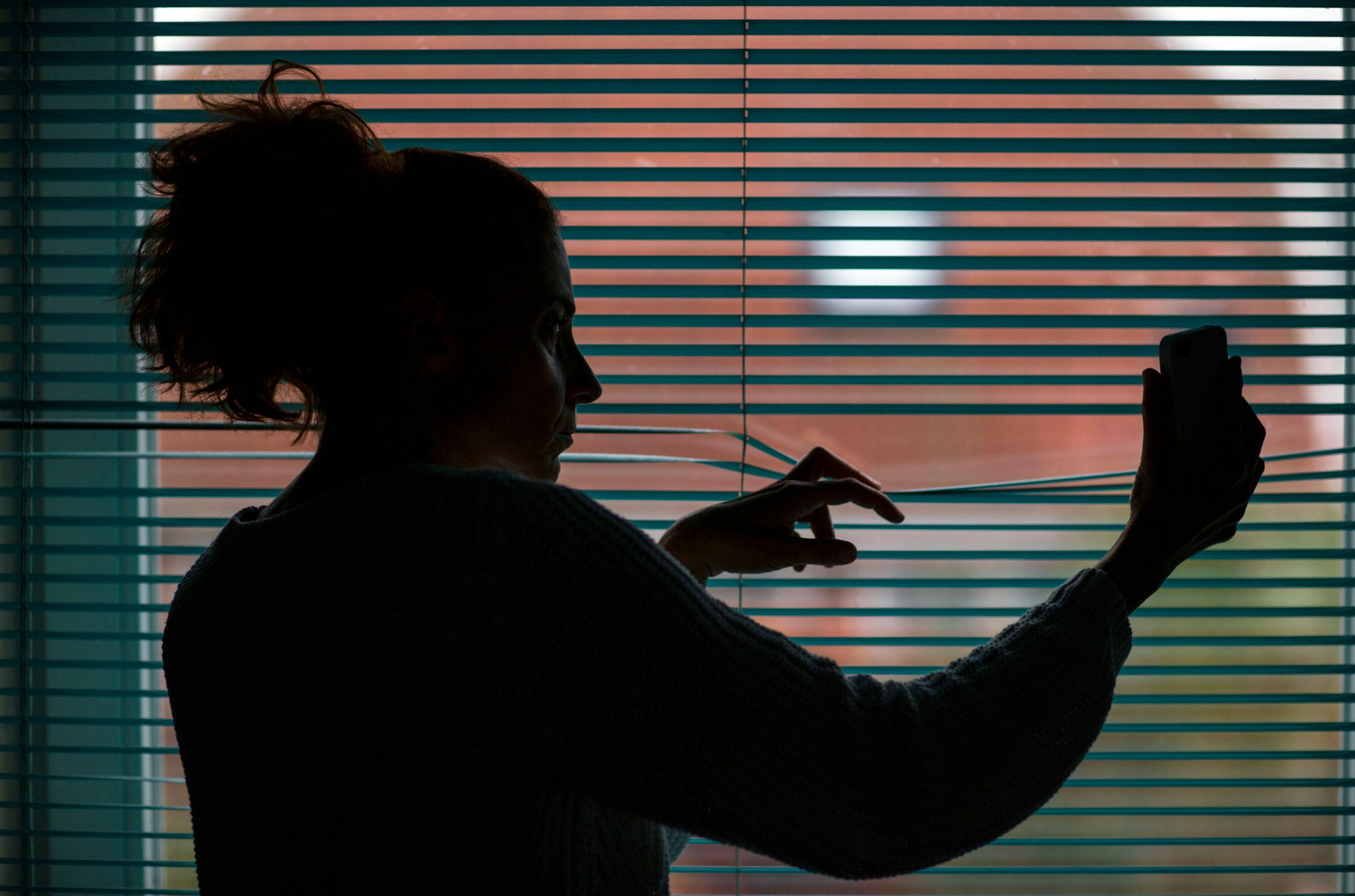 Stalking_Frau schaut aus Fenster_ Symbol