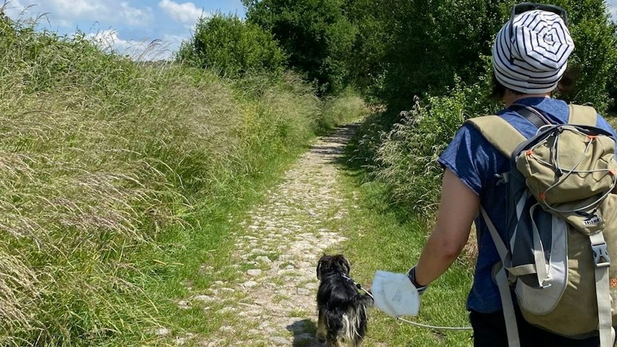 Eine Frau wandert mit Hund über einen mittelalterlichen Verbindungsweg