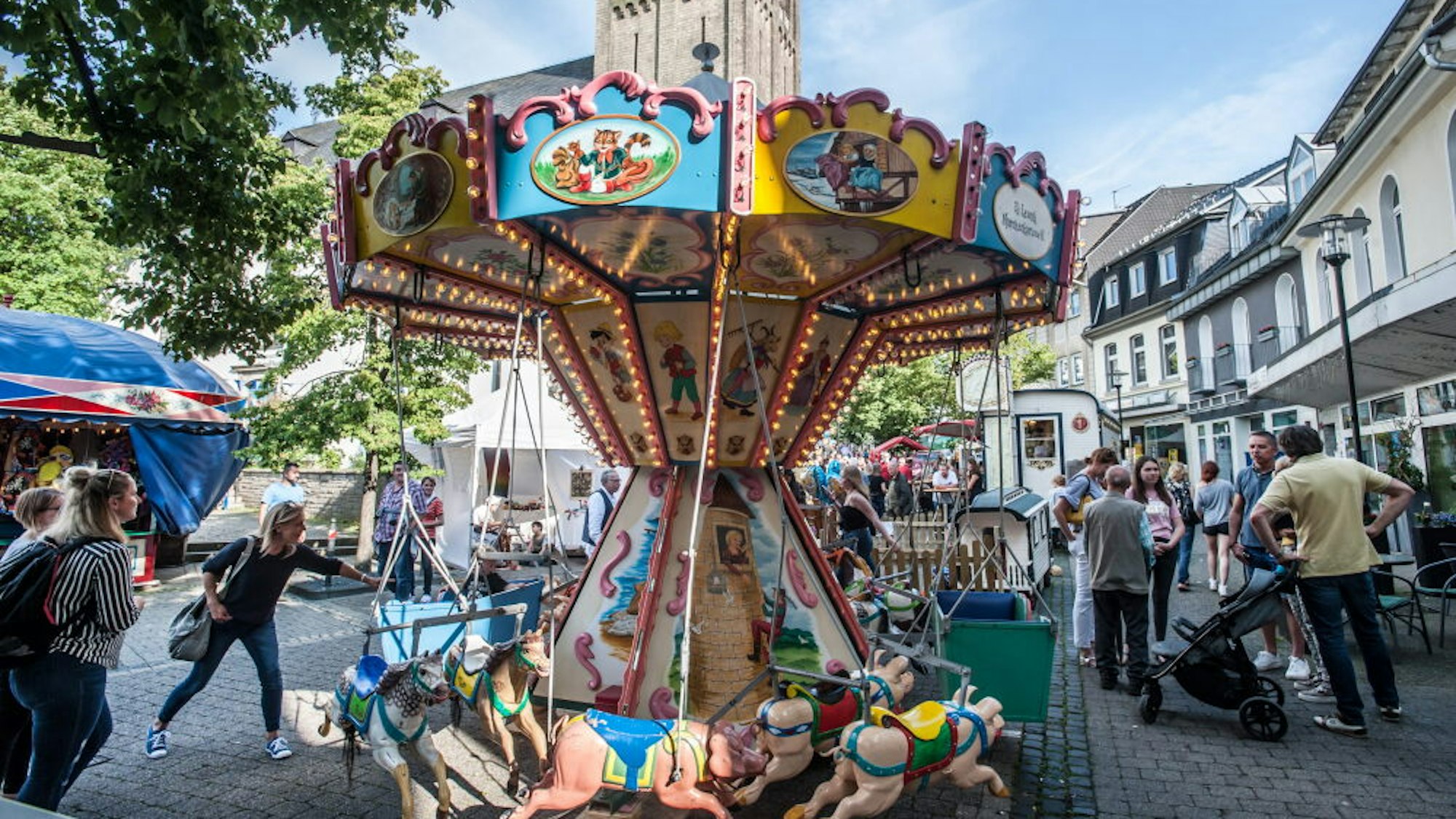 Ein Kinderkarussell steht in Burscheid auf dem Marktplatz, ringsum stehen feiernde Menschen.