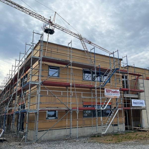 Der Rohbau einer Kita mit Gerüst und Richtkranz.