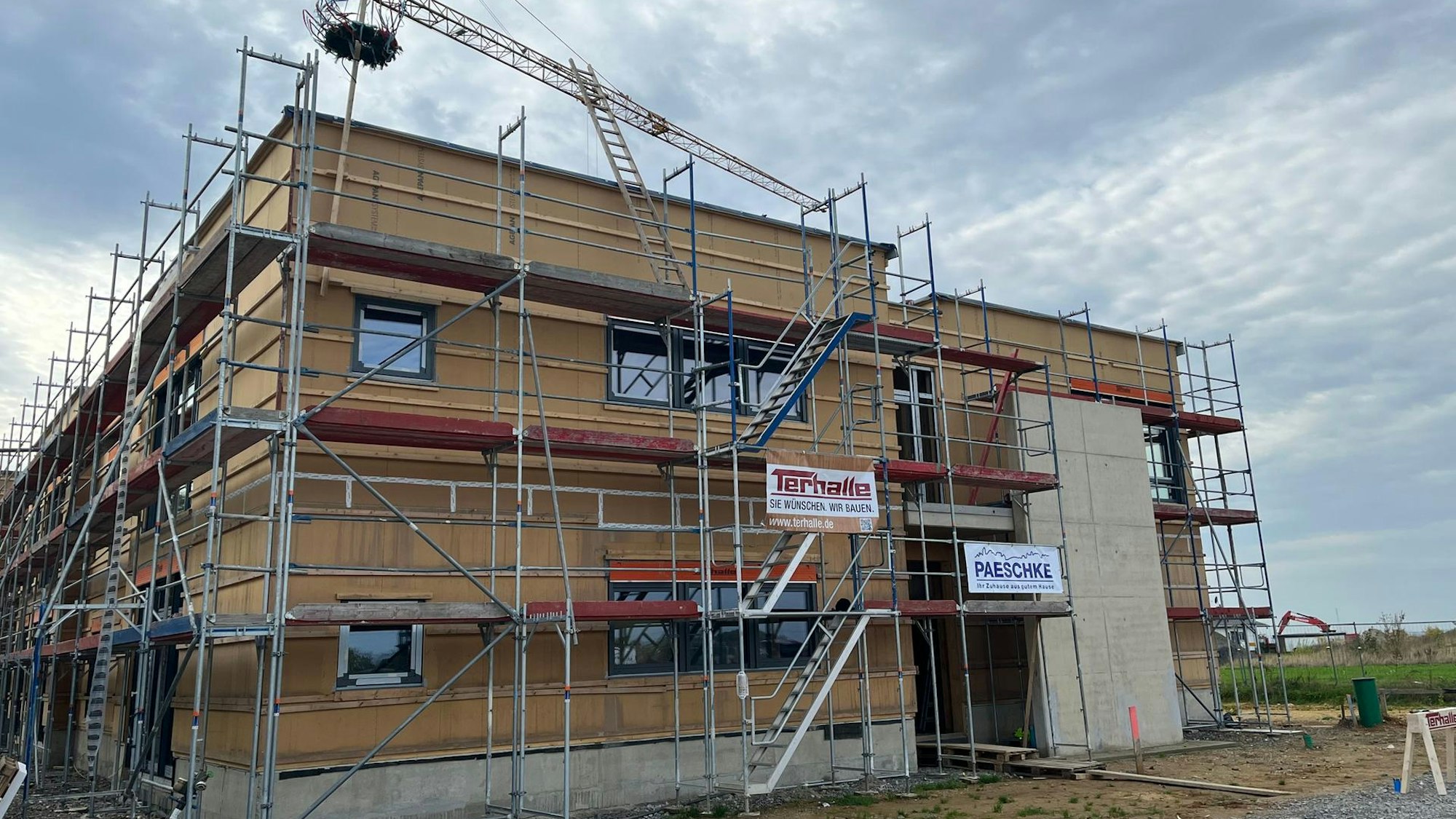 Der Rohbau einer Kita mit Gerüst und Richtkranz.