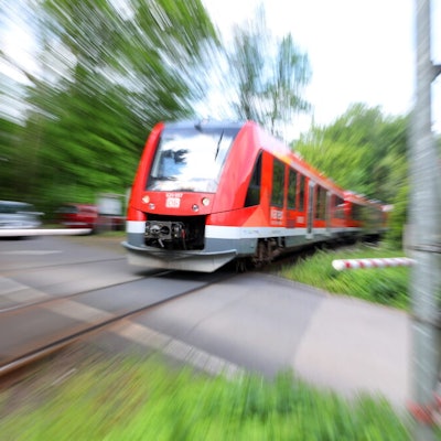 Ein Zug der Oberbergischen Bahn (Köln – Overath – Gummersbach) passiert einen beschrankten Bahnübergang.