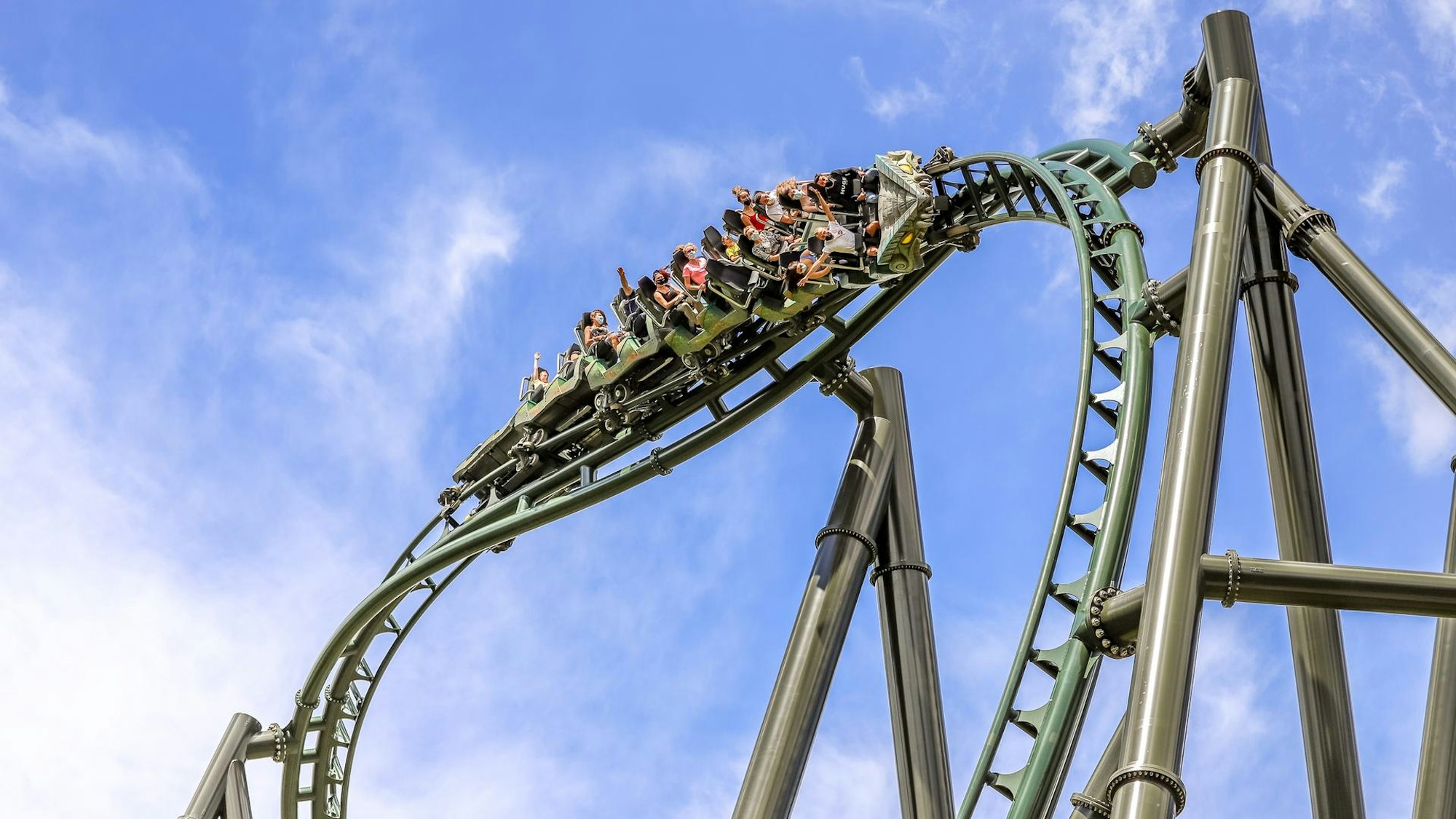 Menschen in einer Achterbahn vor blauem Himmel