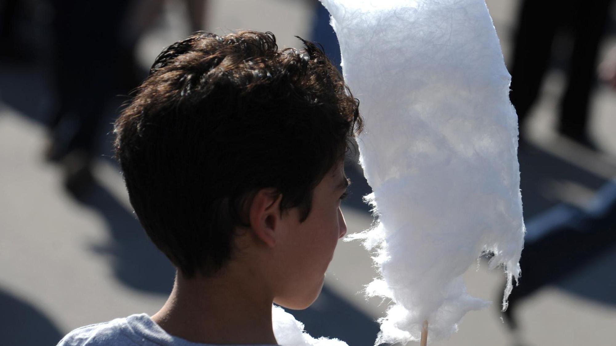 ein Junge hält eine Zuckerwatte in der Hand