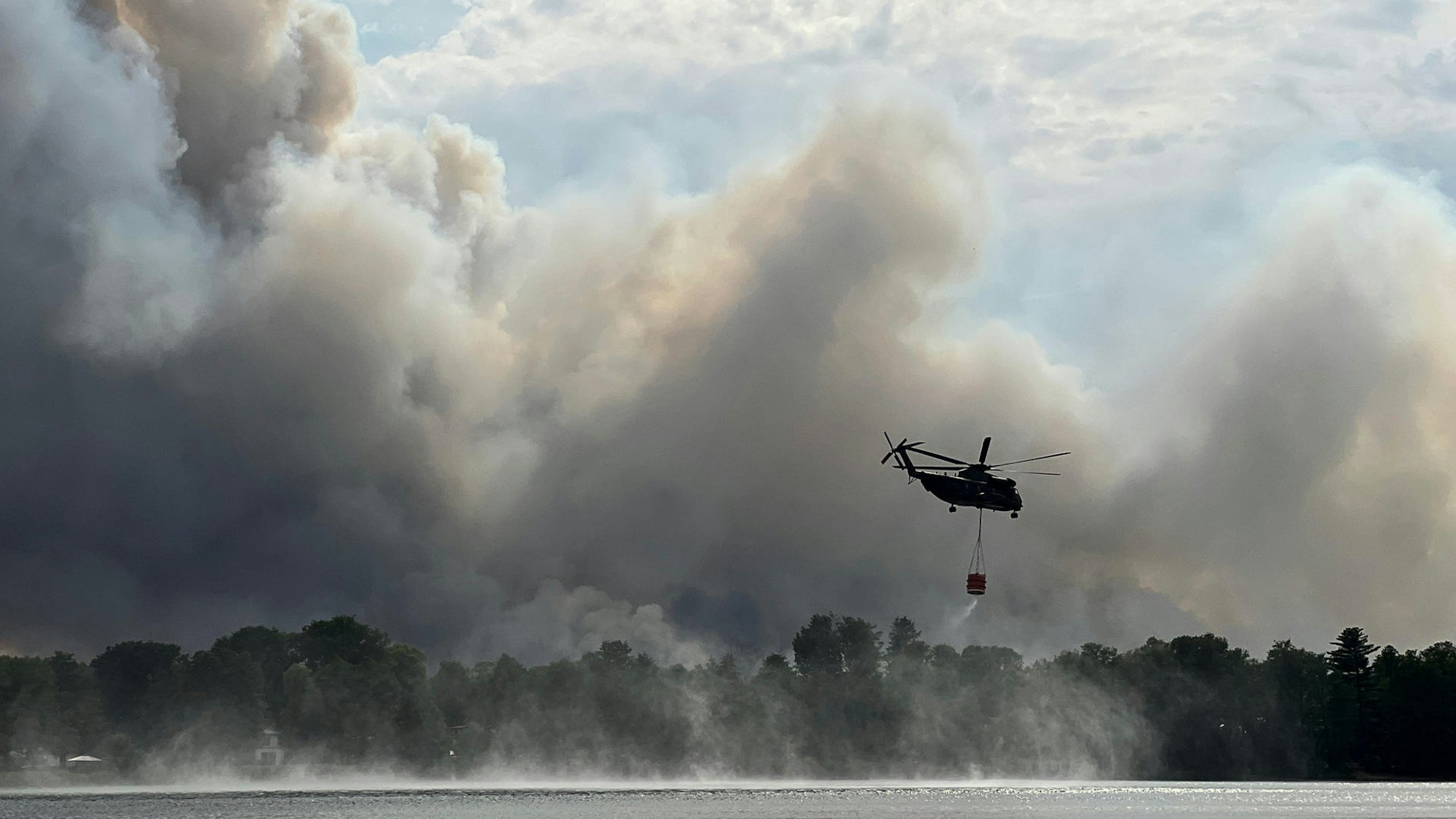 Hubschrauber löscht Feuer.