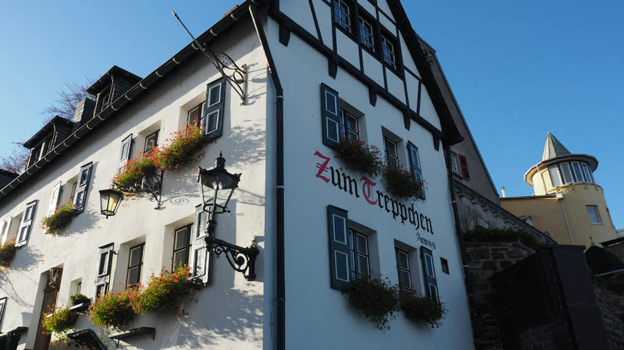 Das Gasthaus „Zum Treppchen“ in Rodenkirchen von außen mit bepflanzten Blumenkästen vor den Fenstern.