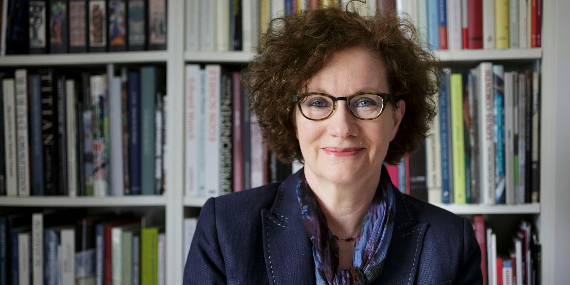 Hannelore Fischer steht vor einer Bücherwand.