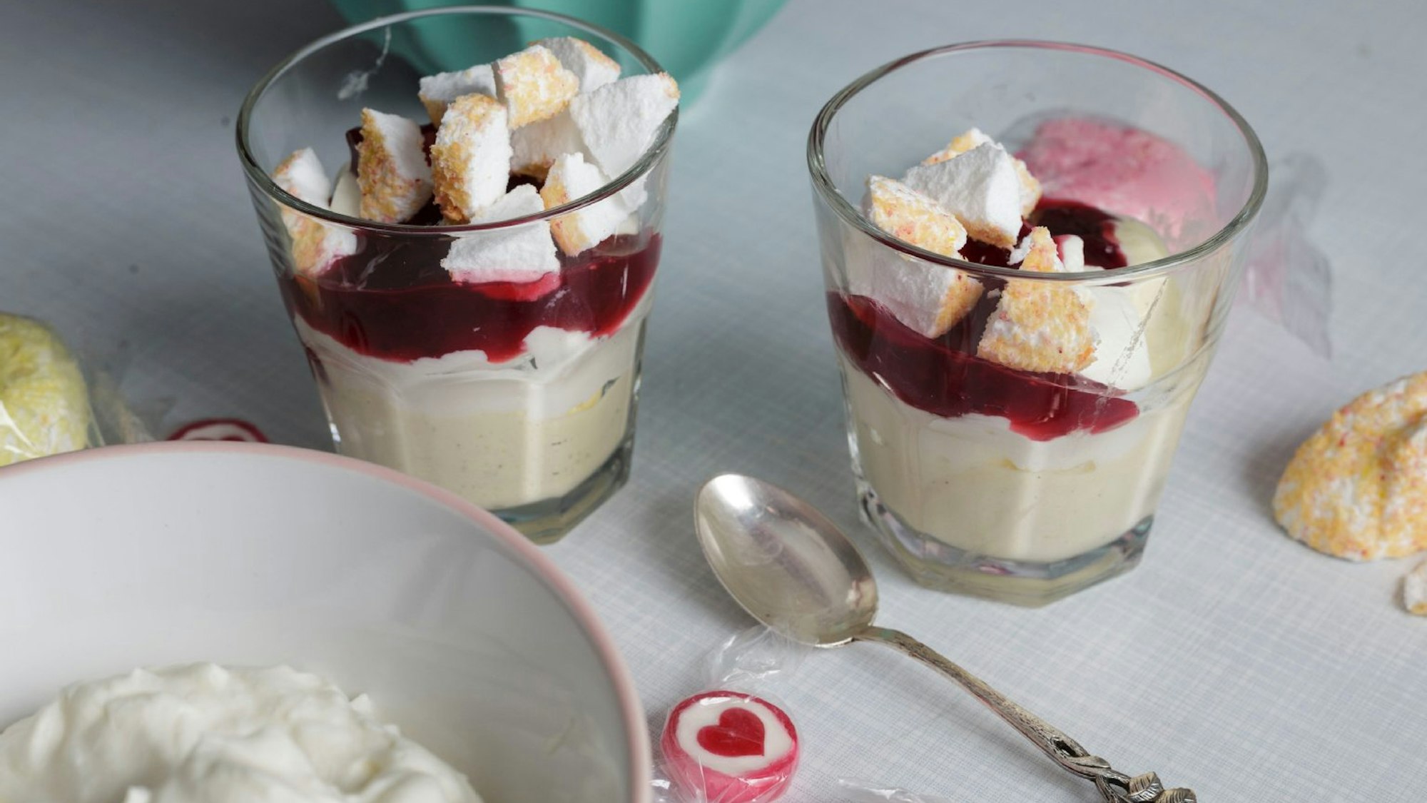 Vanilleeis, Rote Grütze und Kokos-Meringues in zwei Gläsern angerichtet