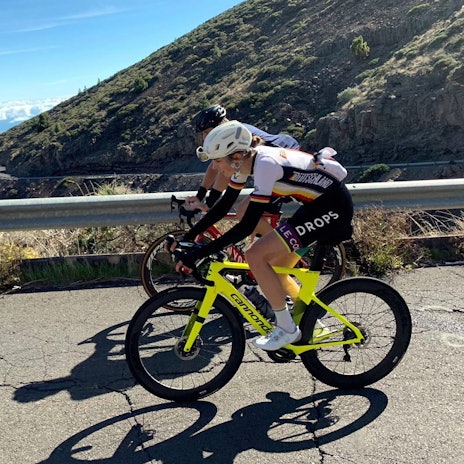 Finja Smelka ist mit einem weiteren Radfahrer auf einer Straße auf ihrem Fahrrad unterwegs.