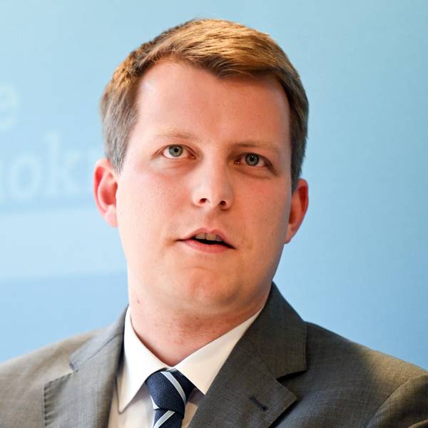 Henning Höne spricht bei einer Veranstaltung. Er ist im Porträt zu sehen vor einer hellblauen FDP-Werbewand.