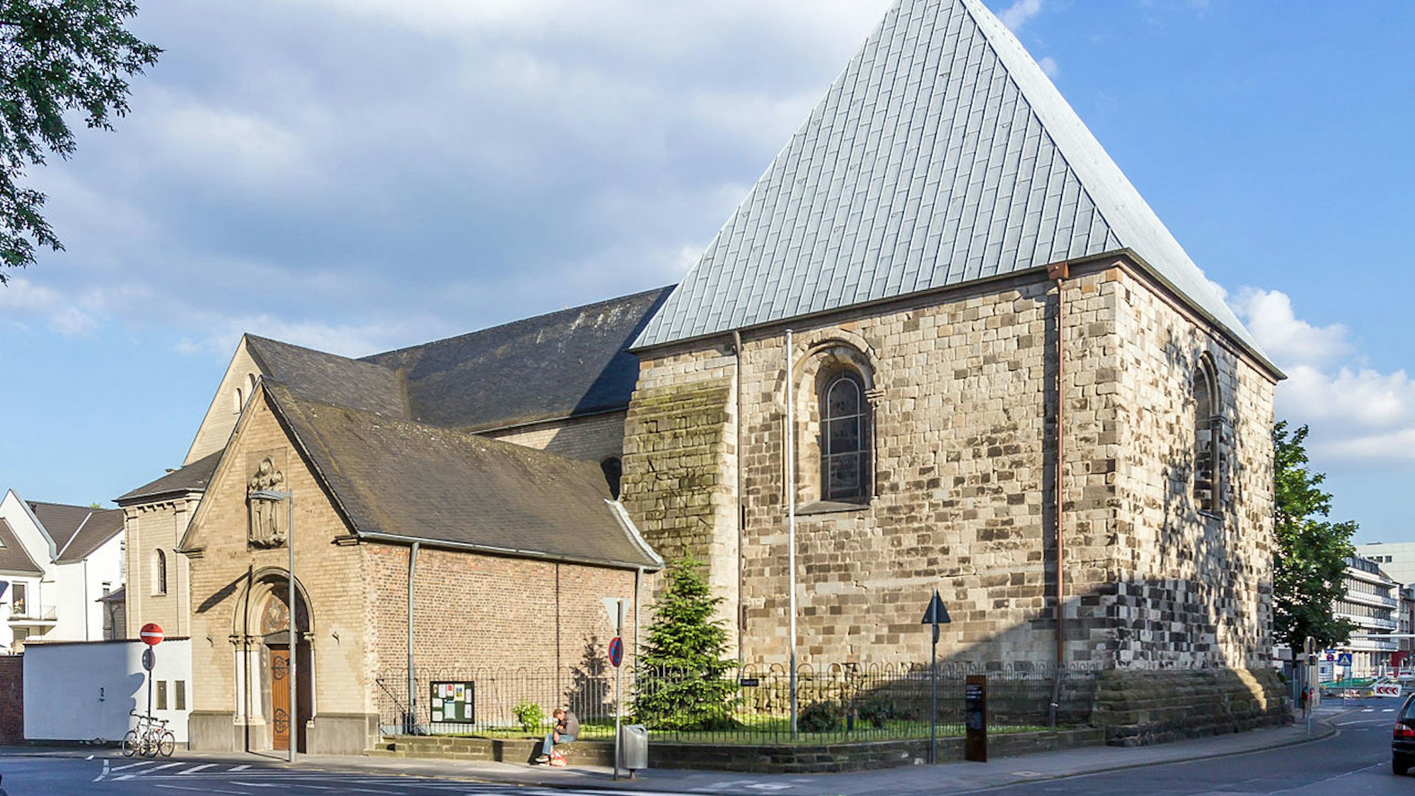 Gebäude mit spitzem Dach, daneben ein Anbau, in dem sich der Eingang befindet