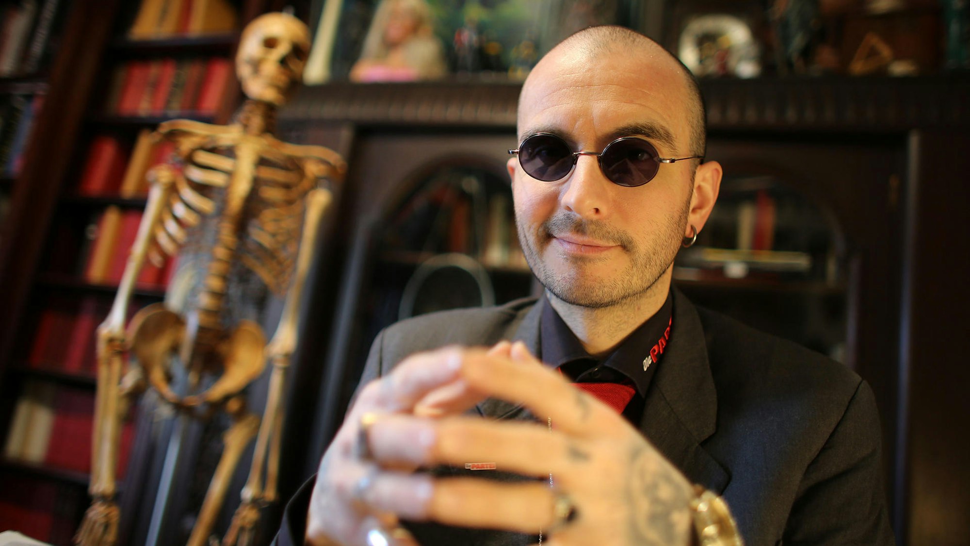 Mark Benecke sitzt in seinem Büro. Im Hintergrund sieht man ein Skelett.