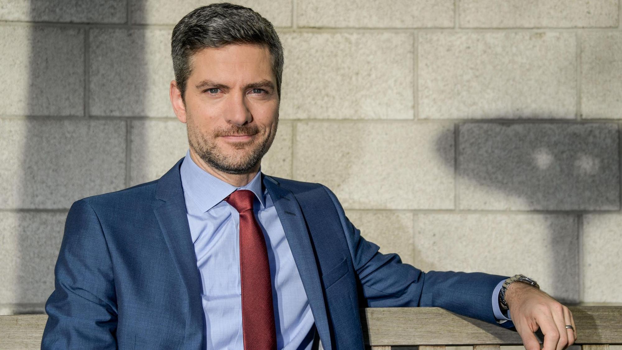 Ingo Zamperoni sitzt auf einer Bank.