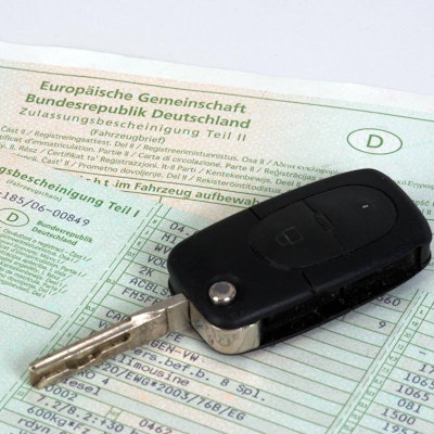 Ein Autoschlüssel liegt auf einem Fahrzeugschein