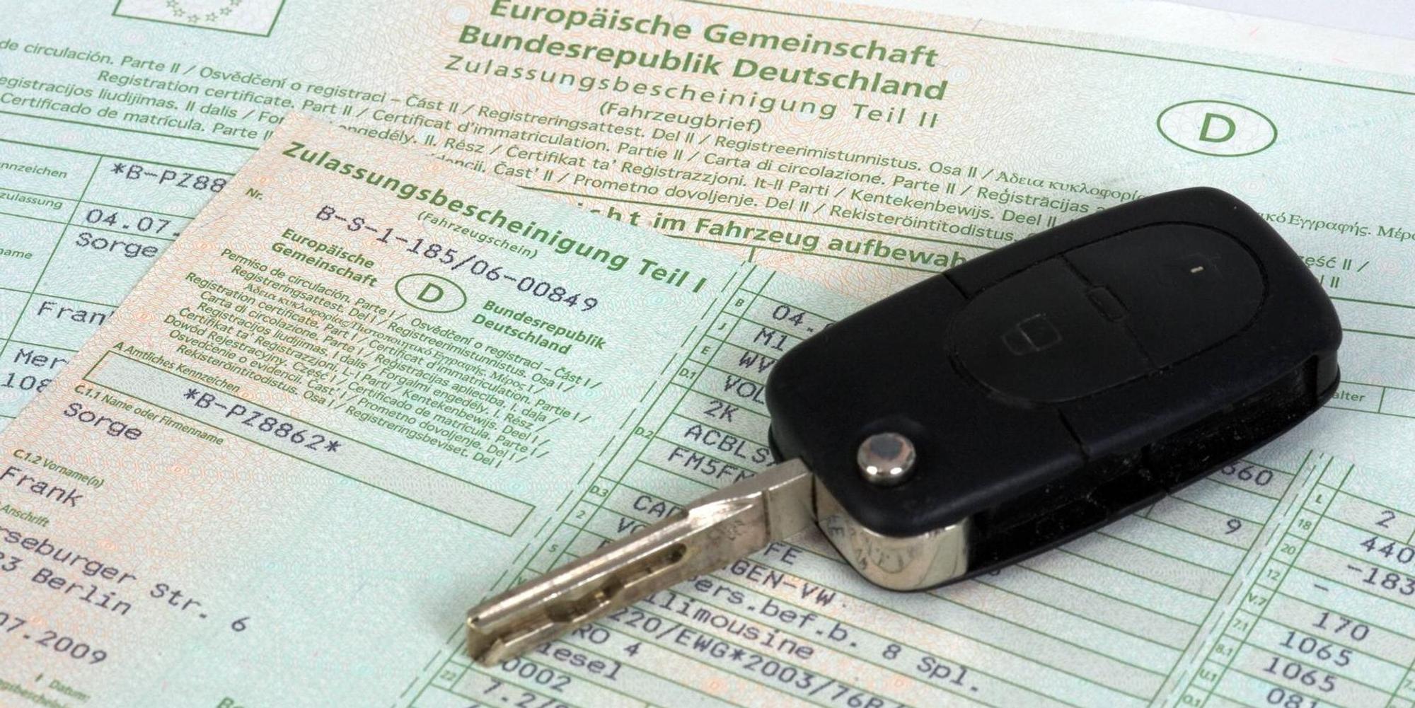 Ein Autoschlüssel liegt auf einem Fahrzeugschein