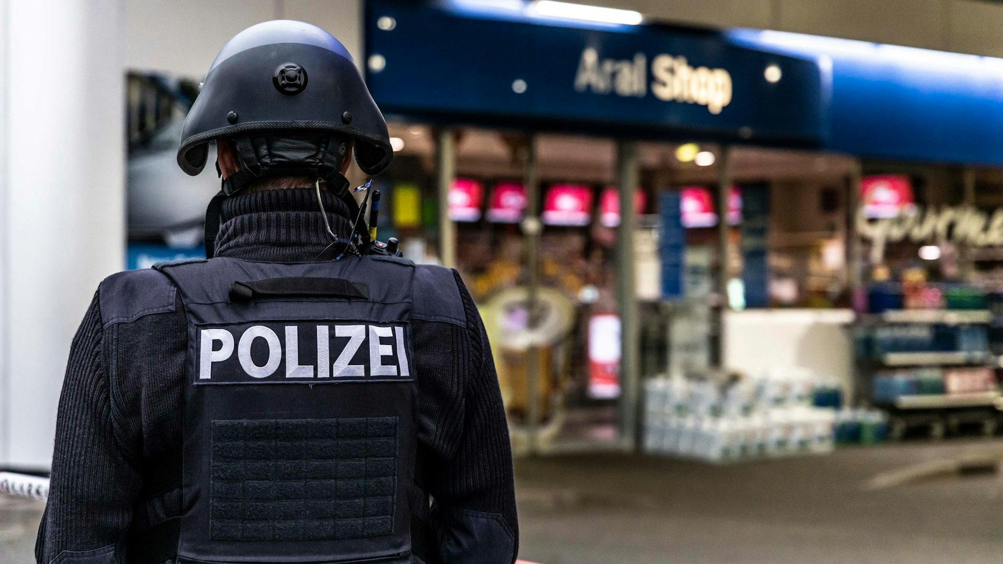 Das Symbolbild zeigt einen Polizisten vor einer Tankstelle. Am Rastplatz Ville-West wurde Mitte November ein Angestellter der Tankstelle überfallen.