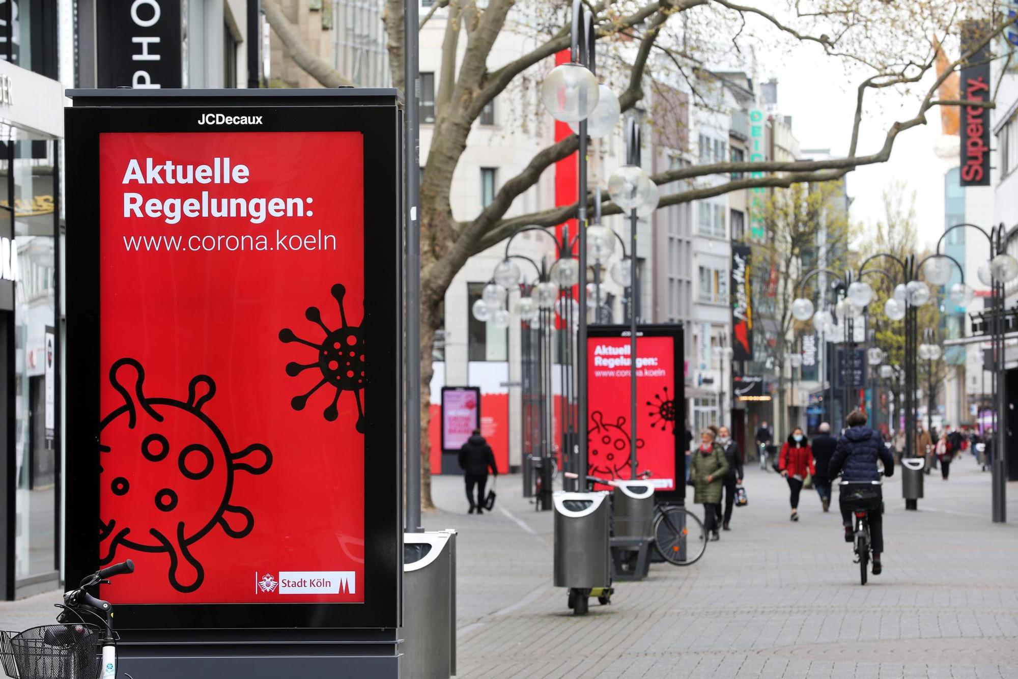 Eine Werbetafel mit einem Info-Plakat zu Corona auf der Schildergasse in Köln.