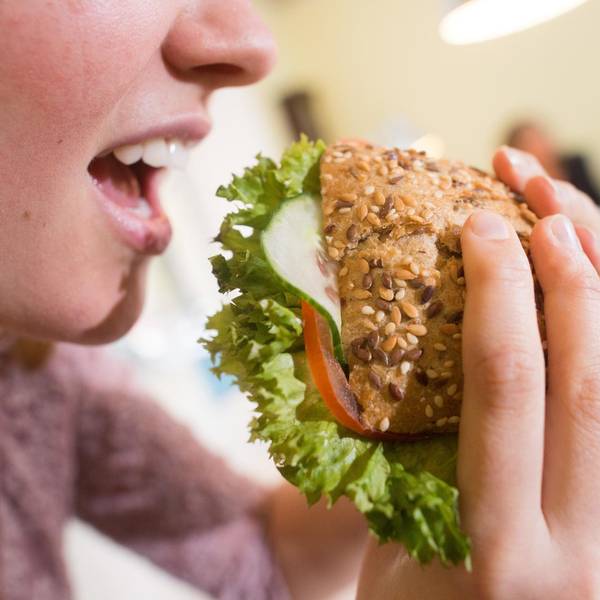 Frau isst ein belegtes Vollkornbrötchen