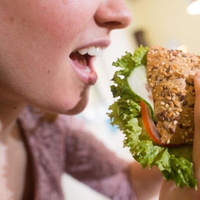 Frau isst ein belegtes Vollkornbrötchen