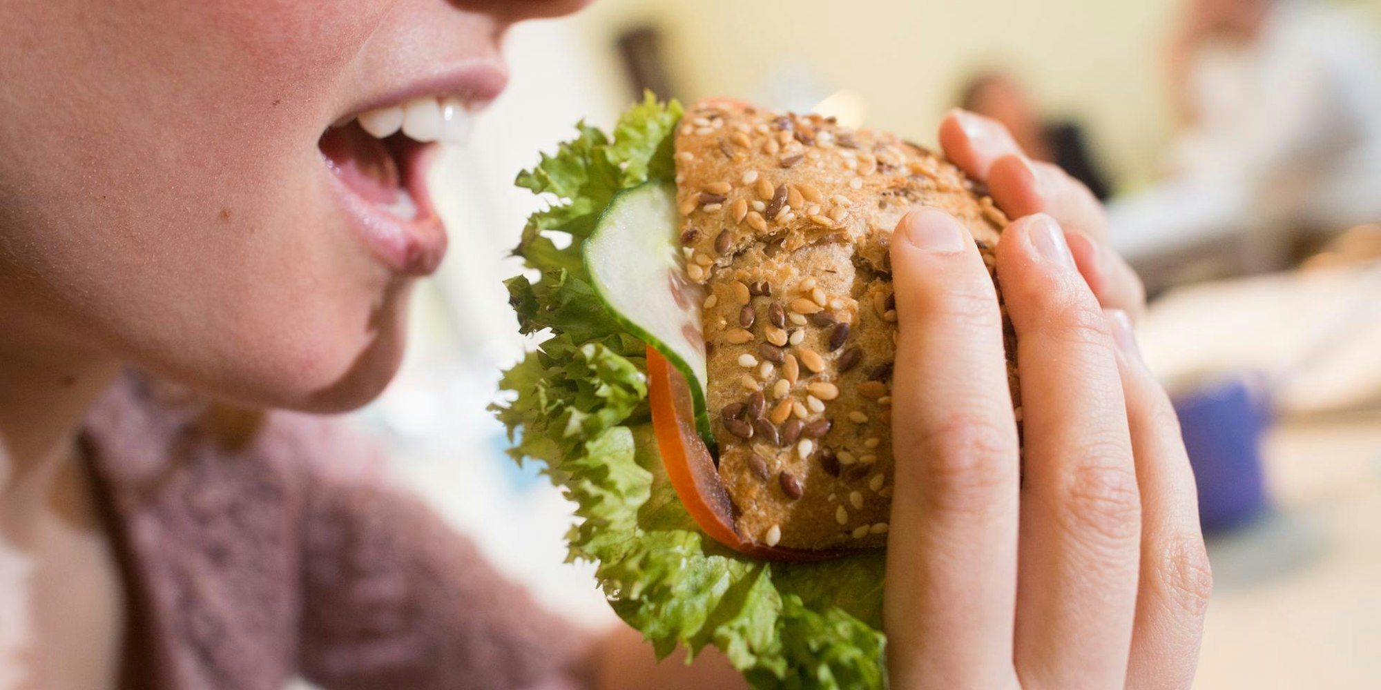 Frau isst ein belegtes Vollkornbrötchen