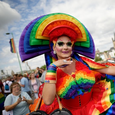Ein bunt gekleideter Mensch beim CSD im Kostüm.