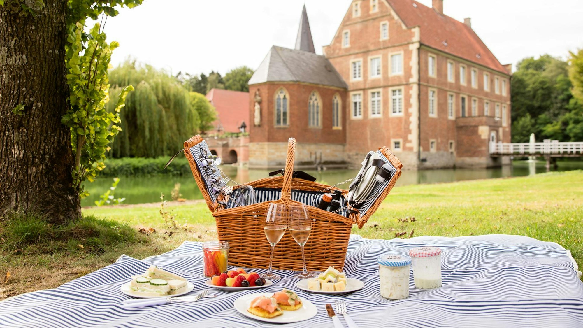 Picknick auf Burg Hülshoff: Eine Decke auf der Wiese, das Essen und der Korb stehen bereit.