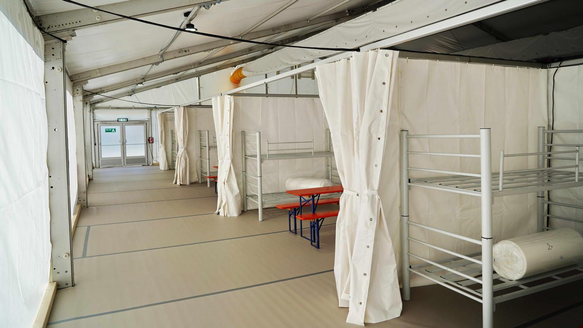 Blick in die ehemalige Notunterkunft am Kölner Südstadion, zu sehen sind weiße Hochbetten, abgetrennt mit weißen Vorhängen