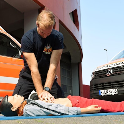 Ein Rettungssanitäter demonstriert an einer Puppe eine Herzdruckmassage.