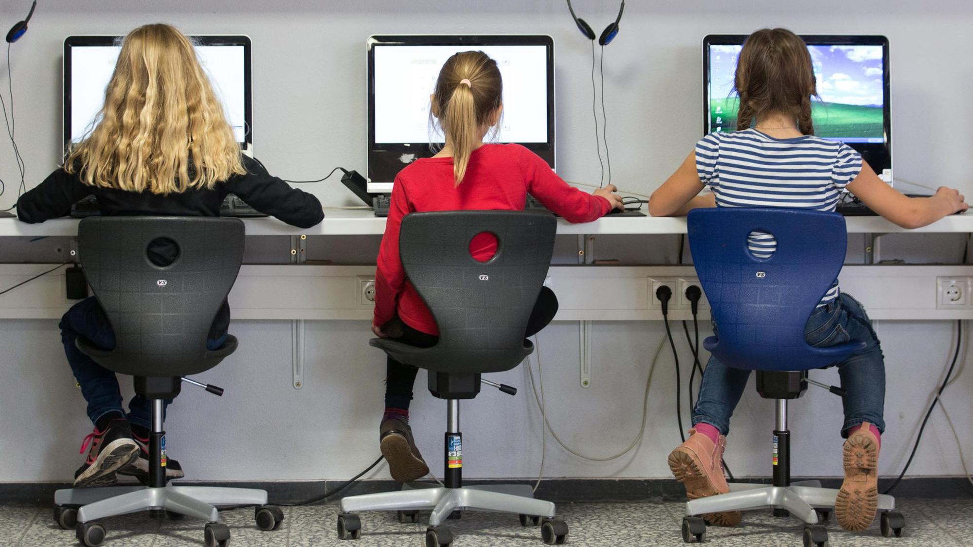 Kinder sitzen vor Computerbildschirmen.