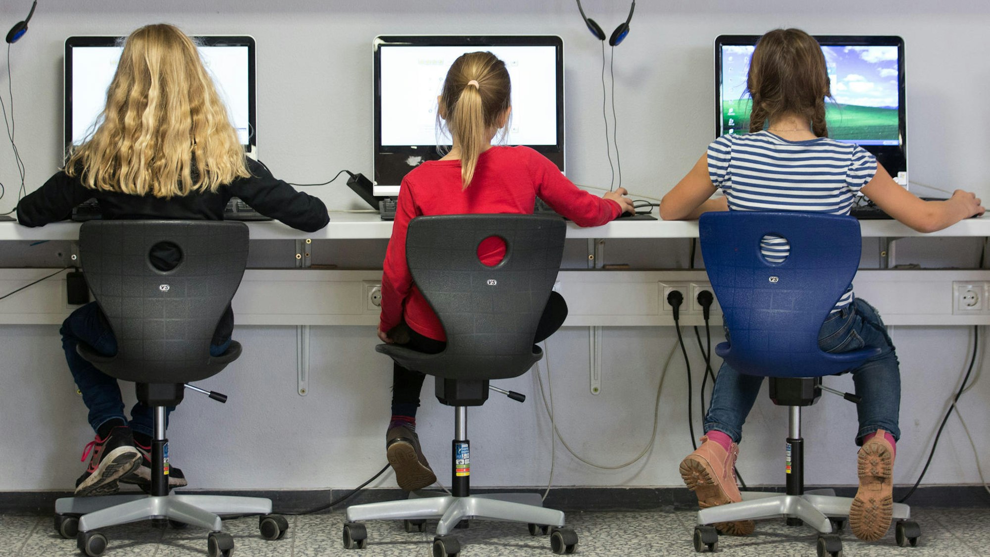 Kinder sitzen vor Computerbildschirmen.