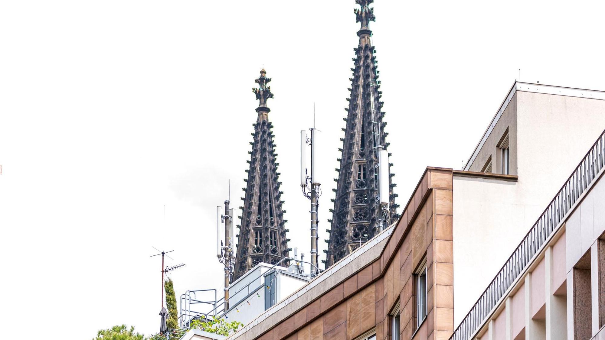 Mobilfunkmasten auf dem Dach eines Hauses in Köln, im Hintergrund die Spitzen des Domes.