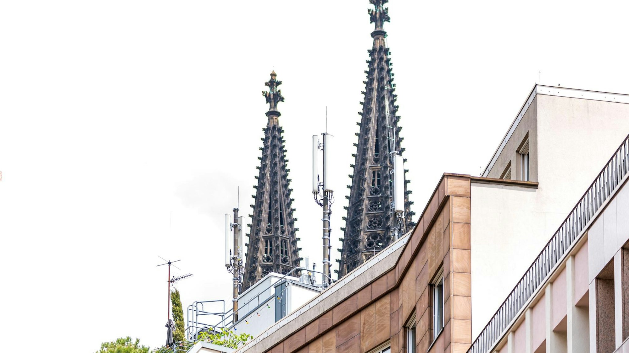 Mobilfunkmasten auf dem Dach eines Hauses in Köln, im Hintergrund die Spitzen des Domes.