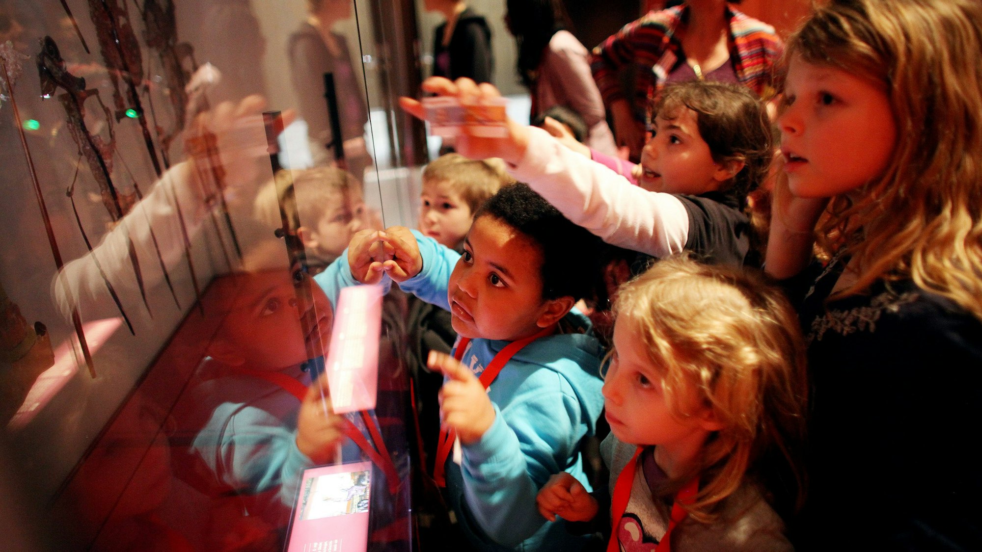 Kinder vor der Scheibe eines Ausstellungskastens