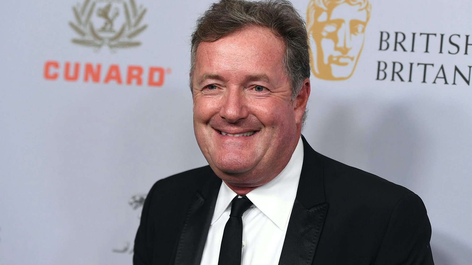 Piers Morgan bei einem öffentlichen Termin vor einer Fotowand.