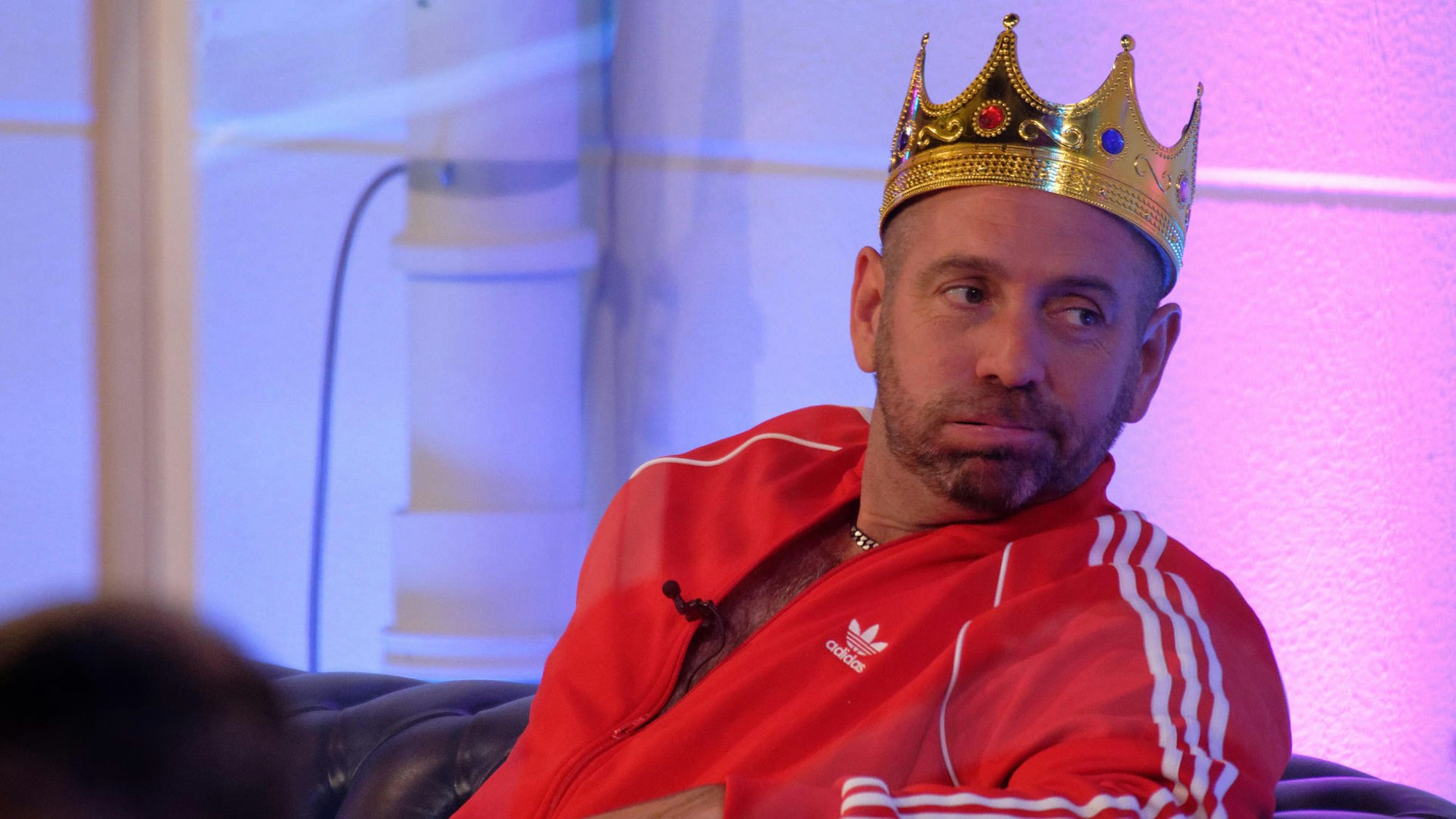 Ikke Hüftgold macht mit Papierkrone auf dem Kopf dicke Backen.