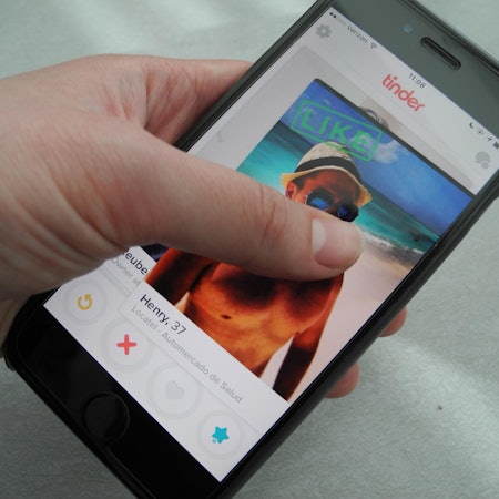 Eine_Frau_hält_ihr_Smartphone_in_der_Hand_auf_dem_Bildschirm_ist_die_App_Tinder