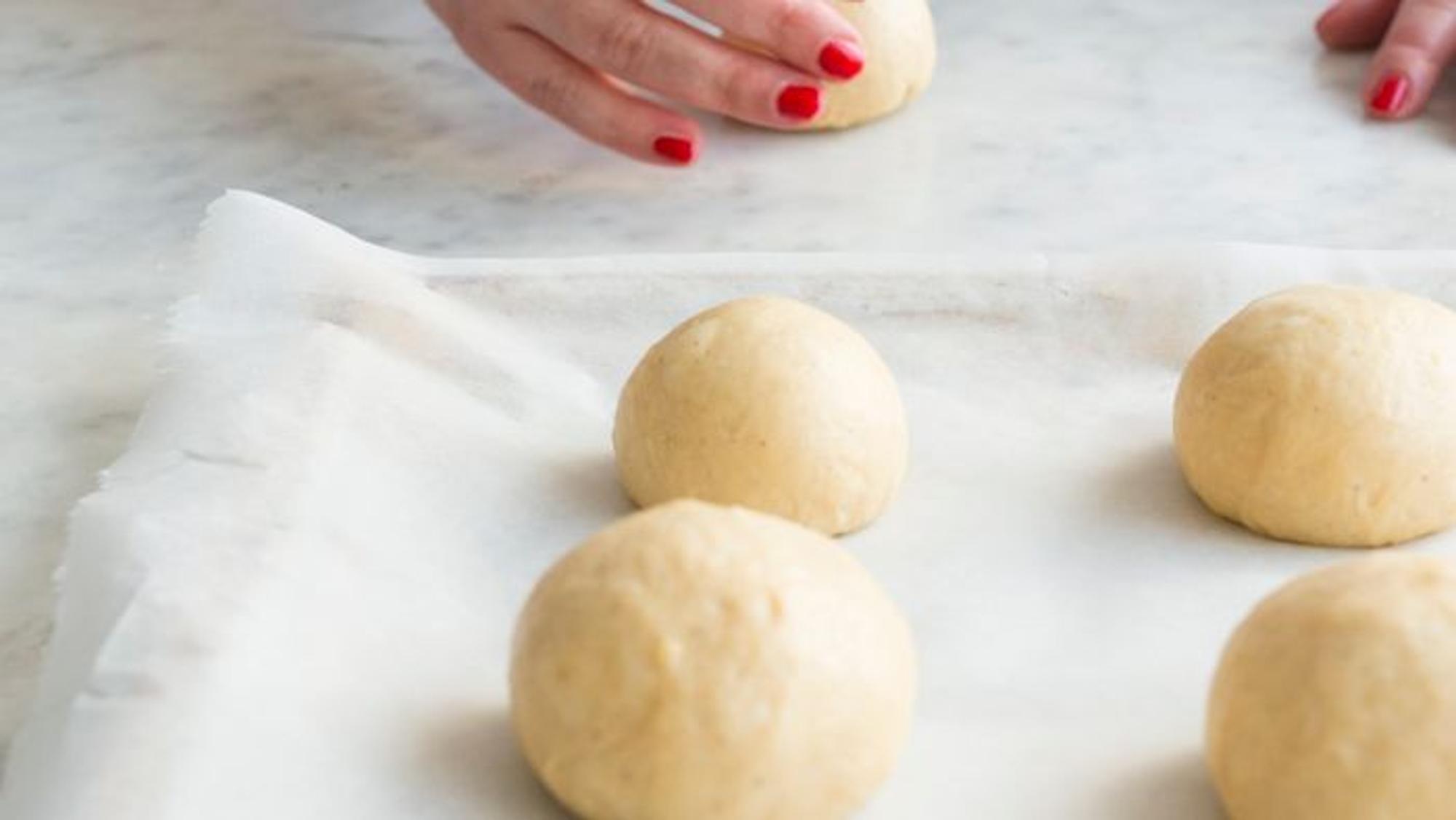 Hände rollen Kugeln aus Teigfladen.