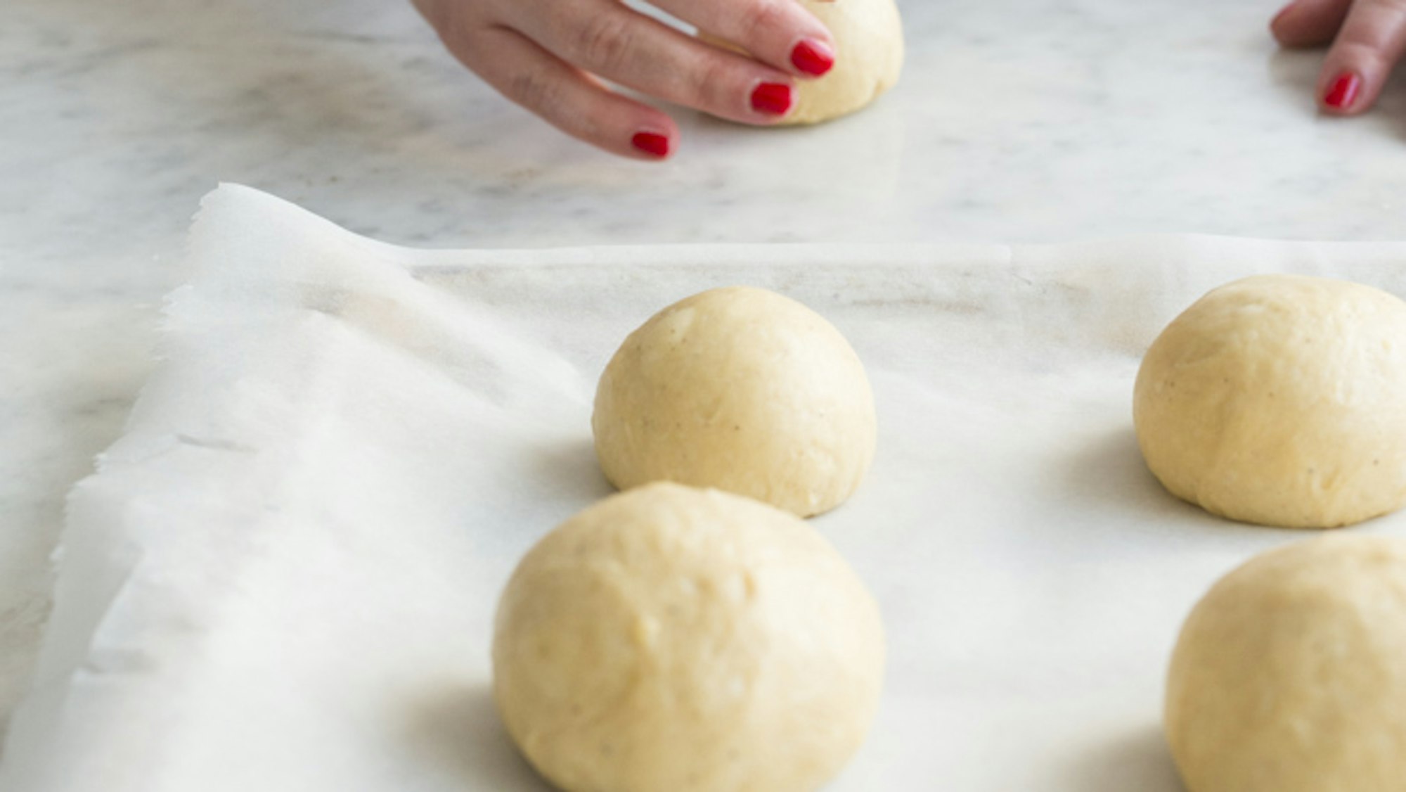 Hände rollen Kugeln aus Teigfladen.