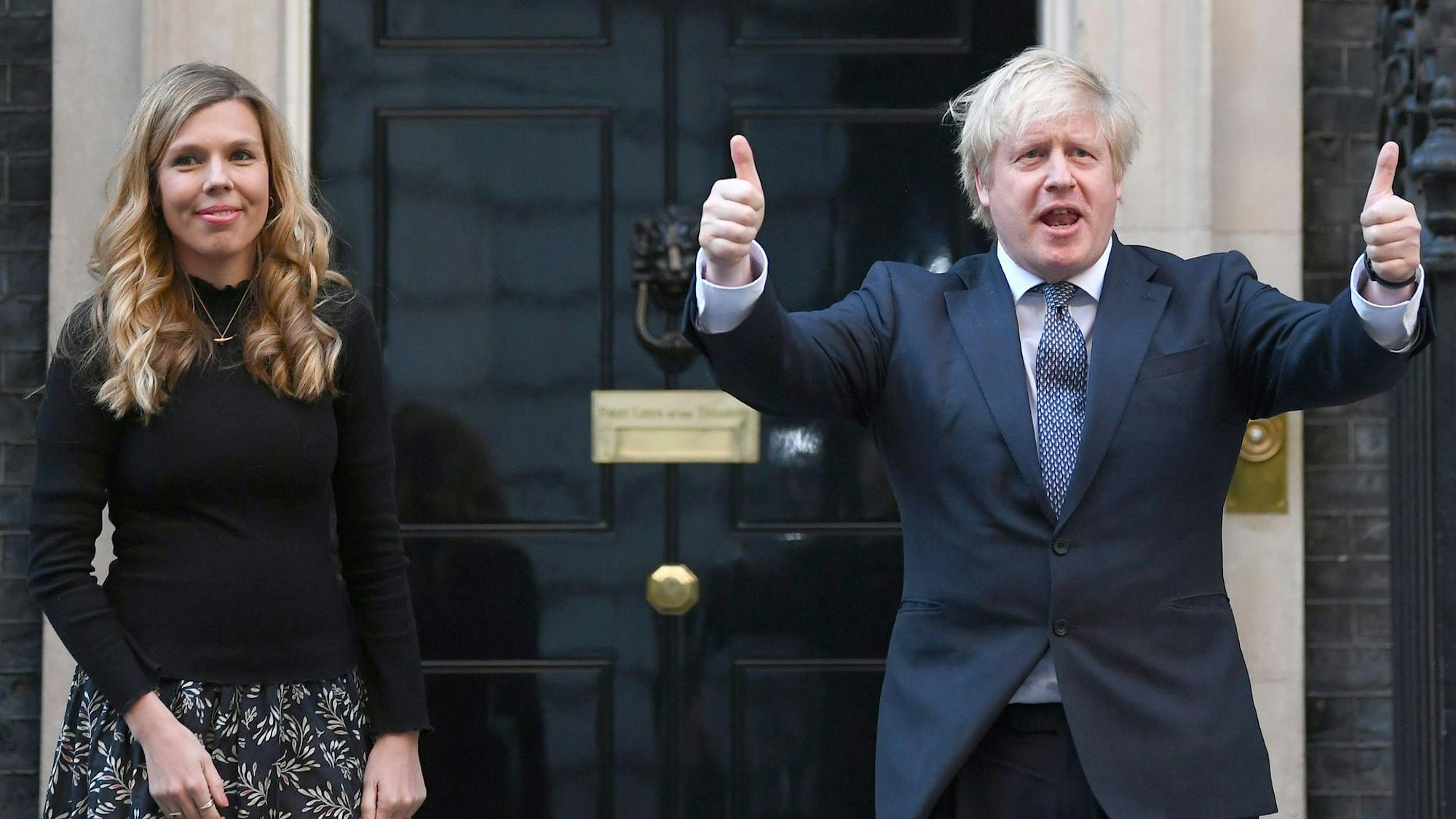 Carrie und Boris Johnson stehen draußen. Er macht beide Daumen hoch.