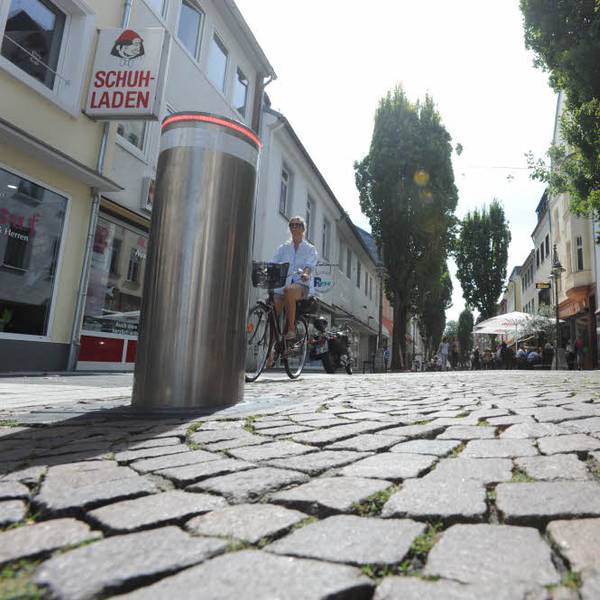 Das Foto zeigt eine Straße mit zwei versenkbaren Pollern im Vordergrund.