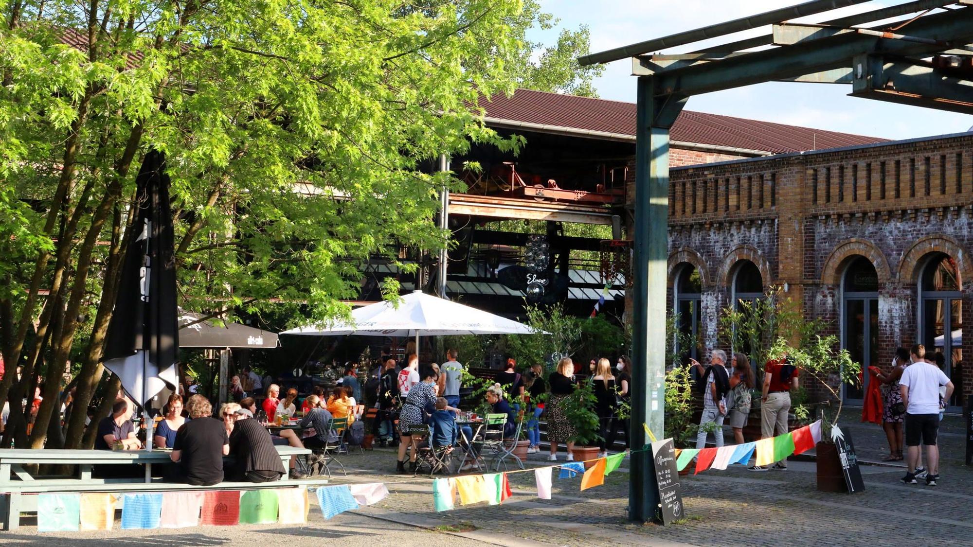 Biergarten mit vielen Menschen und bunten Fahnen