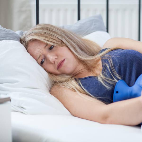 Frau liegt mit Bauchschmerzen im Bett
