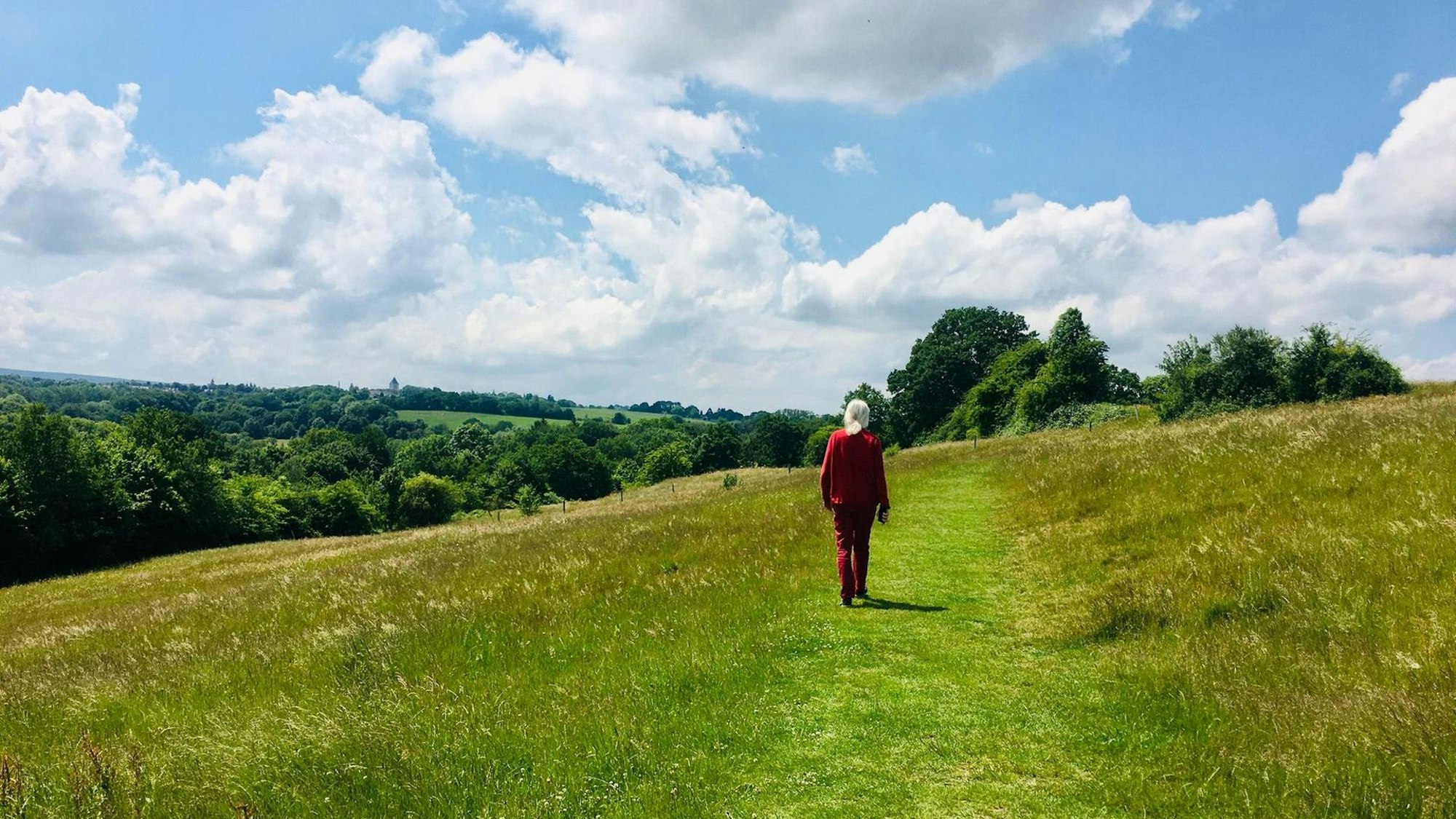 Eine Frau wandert auf der Inde-Route über eine Wiese.