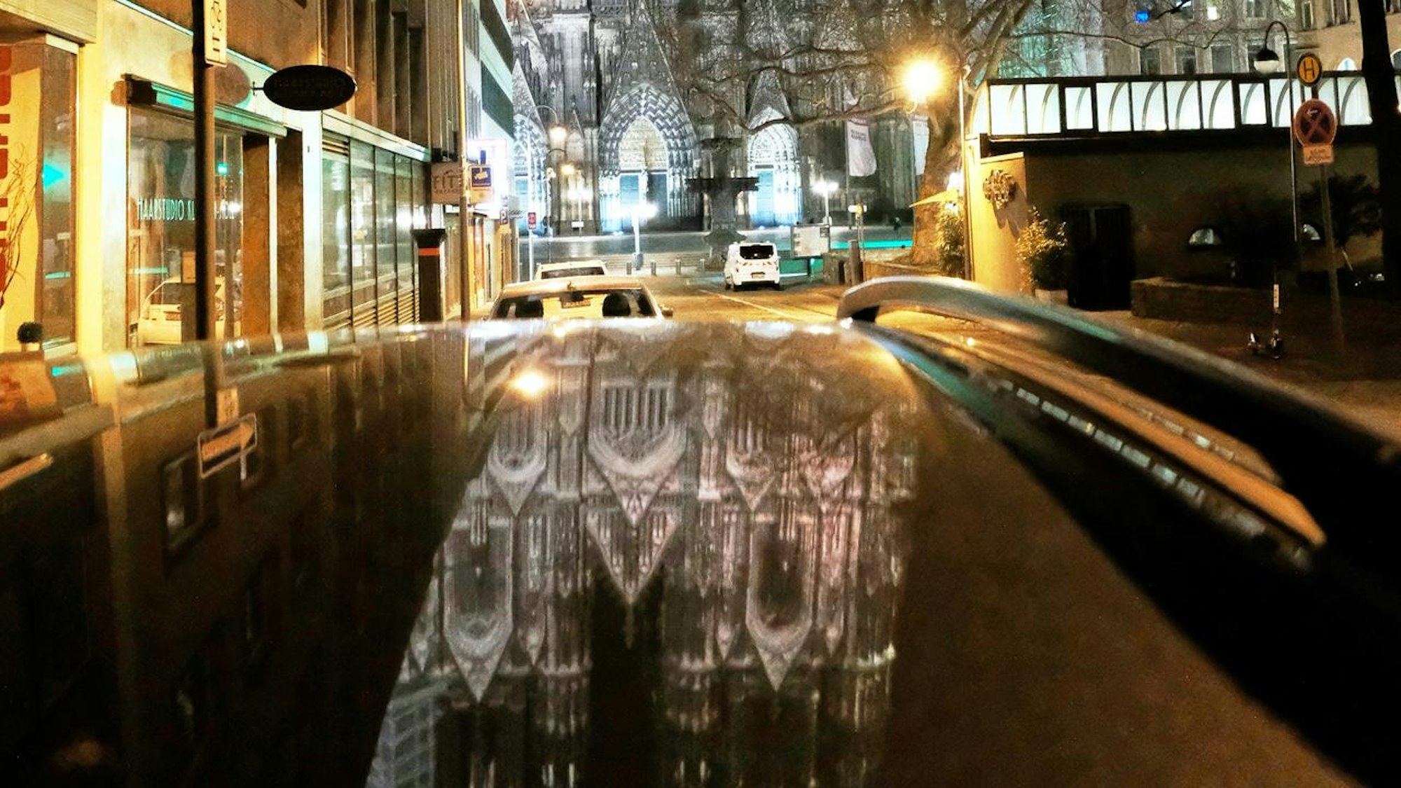 Der Dom spiegelt sichauf einem schwarzen Autodach.