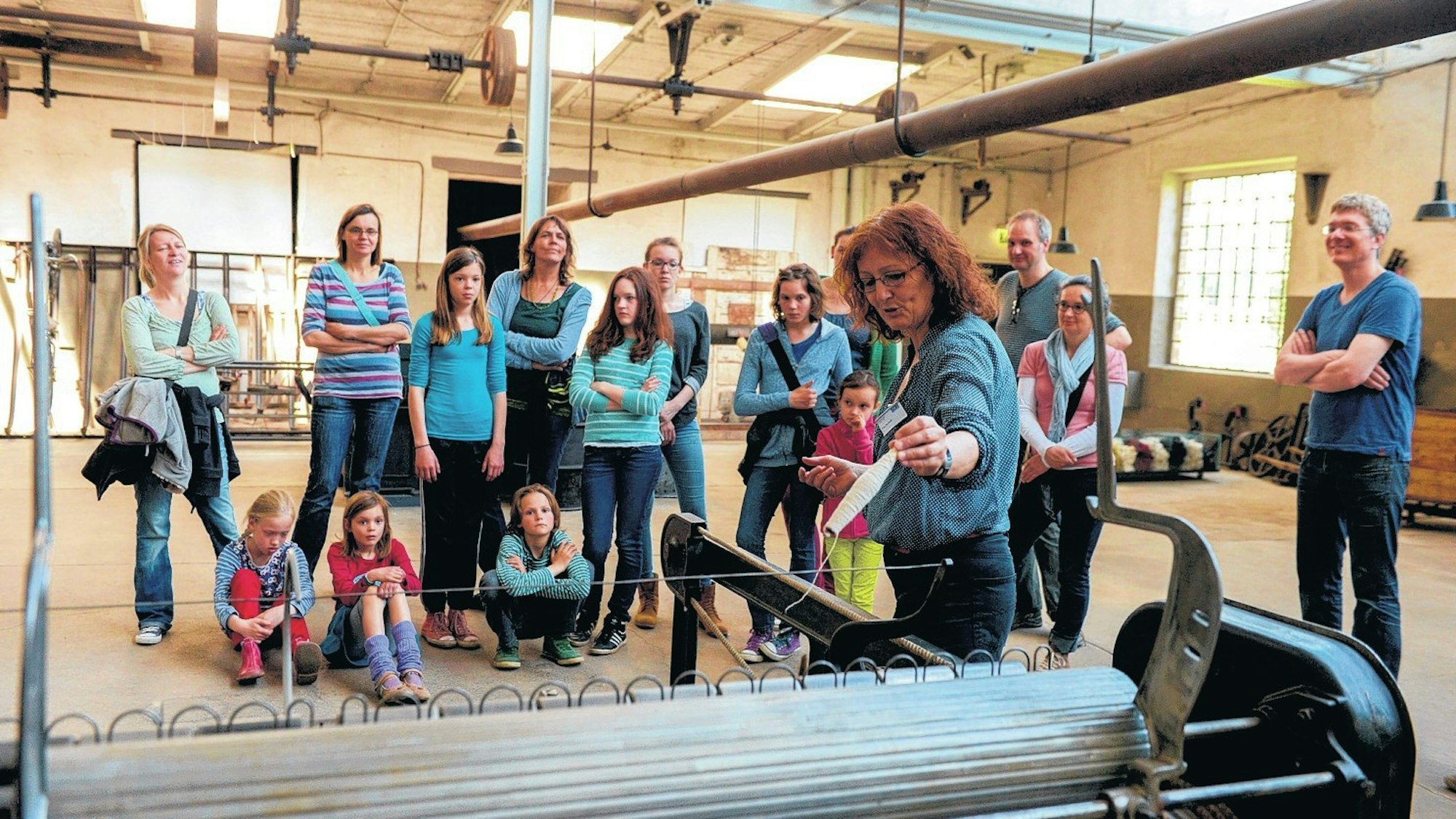 eine Frau zeigt etwas an einer Maschine, vor ihr steht eine Gruppe aus Kindern und Erwachsenen